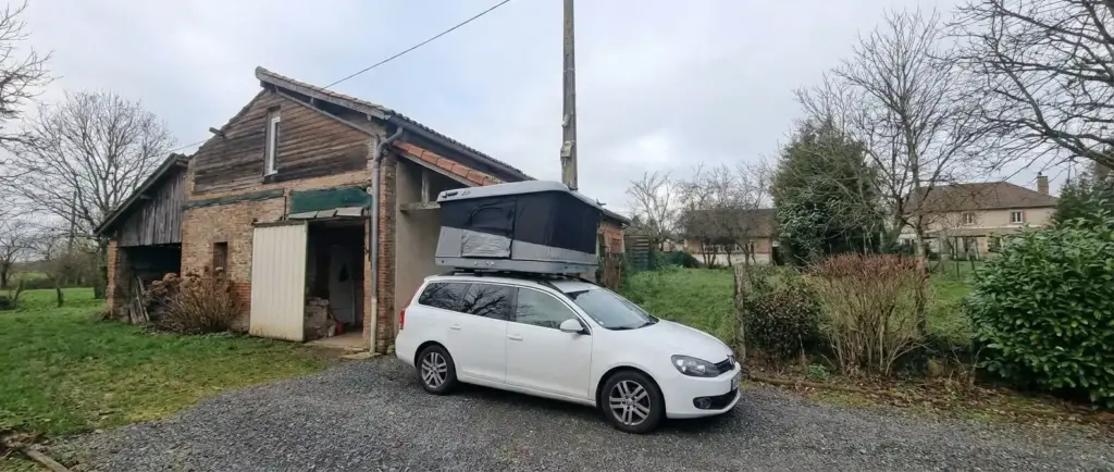 Tente de toit James Baroud Evasion installée sur une voiture break blanche devant une maison