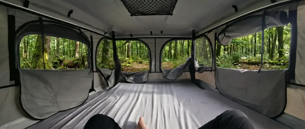 Bivouac en forêt vue intérieur tente de toit James Baroud Evasion sur le lit
