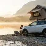 Peugeot 3008 blanc avec tente de toit souple déployée stationné en bord de lac